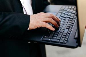 afbeelding bijsnijden van senior zakenman die laptop in zijn hand houdt en close-up typt.- afbeelding foto