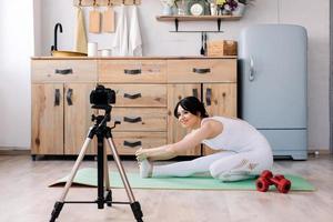 mooie jonge vrouw die lacht en video maakt over haar sporttraining foto