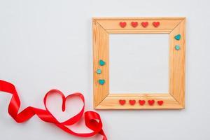 houten frame versierd met hartjes en bekleed hart met rood lint op een witte achtergrond. Valentijnsdag concept foto