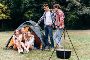 een gezelschap van vrienden naast de tent. - kampeerconcept foto