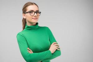 serieuze jonge vrouw in glazen en in casual kleding poseren in de studio met kruisende handen. horizontale afbeelding foto