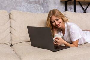 jong mooi vrouw gebruik makend van laptop computer glimlachen gelukkig aan het kijken en browsen of aan het doen online internet boodschappen doen Bij huis. foto