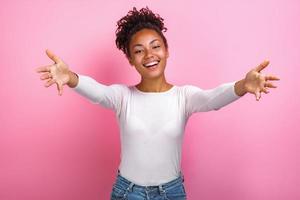 studio portret van vrouw brede armen uit elkaar poseren over roze achtergrond kijken naar camera, concept van vriendschap - afbeelding foto