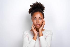 close-up portret van een mooi serieus meisje over een lichte achtergrond raakt zichzelf aan het gezicht - afbeelding foto