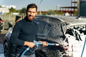 taille portret van de man met een hogedrukspuit voor het wassen van auto's. concept desinfectie en antiseptische reiniging van het voertuig foto