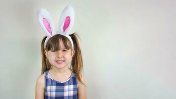 schattig glimlachen weinig meisje met konijn oren Aan een grijs achtergrond. Pasen viering concept foto