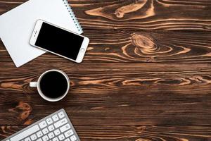 bovenaanzicht houten bureau met een kopje koffie en smartphone foto