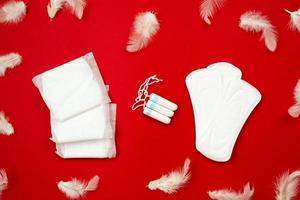 witte tampons, vrouwelijke pakkingen op rode achtergrond. concept van kritieke dagen, menstruatie foto