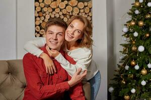 gelukkig jong lief paar Aan leven kamer zittend Aan de bankstel in de buurt kerst boom foto