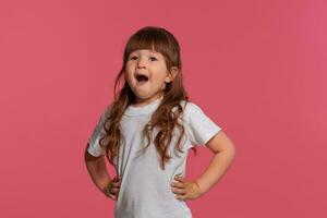 detailopname portret van een weinig brunette meisje gekleed in een wit t-shirt poseren tegen een roze studio achtergrond. oprecht emoties concept. foto