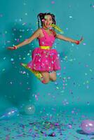 lief meisje met een veelkleurig vlechtjes kapsel en helder verzinnen, poseren in studio met lucht ballonnen en confetti tegen een blauw achtergrond. foto