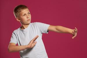 detailopname portret van een blond tiener- jongen in een wit t-shirt poseren tegen een roze studio achtergrond. concept van oprecht emoties. foto