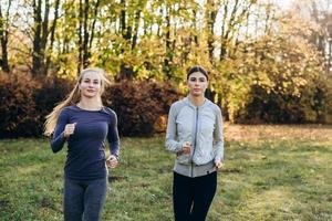twee schattige, fitness meisjes joggen in het park. foto