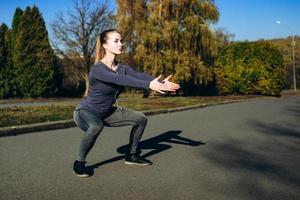 meisje in sportkleding en koptelefoon die sit-ups doet terwijl ze buiten traint. foto