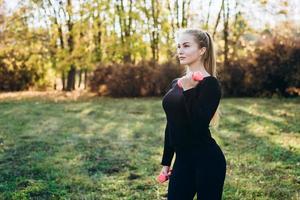 atletisch meisje doet fitness buitenshuis met halters, zijaanzicht. foto