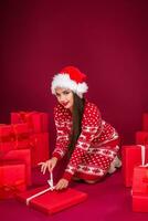 jong Kaukasisch vrouw is zittend Aan de verdieping omringd door boodschappen doen Tassen en Kerstmis geschenken. foto