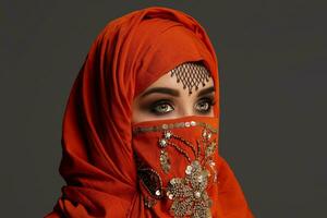 studio schot van een jong charmant vrouw vervelend de terracotta hijab versierd met pailletten en sieraden. Arabisch stijl. foto