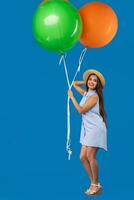 volledige lengte schot van glimlachen jong vrouw op zoek camera en Holding kleurrijk lucht ballonnen geïsoleerd over- blauw foto
