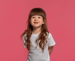 detailopname portret van een weinig brunette meisje gekleed in een wit t-shirt poseren tegen een roze studio achtergrond. oprecht emoties concept. foto