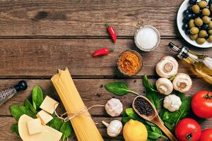 pasta ingrediënten - tomaten, olijf- olie, knoflook, Italiaans kruiden, vers basilicum, zout en spaghetti Aan een houten achtergrond met kopiëren ruimte, horizontaal, top visie foto