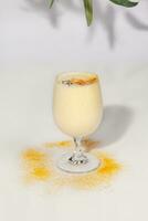 fruitig lassi met yoghurt en mango pulp besprenkeld met kurkuma poeder foto