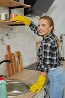 vrouw in handschoenen schoonmaak meubilair met vod Bij huis keuken. foto