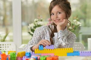 portret van schattig meisje spelen met kleurrijk plastic blokken in kamer foto