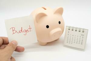 begroting tekst Aan papier, varkentje bank met 2024 jan kalender Aan een wit achtergrond. financiën, geld beheer concept. foto
