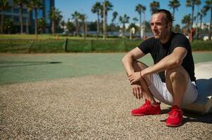 knap Kaukasisch sportman ontspannende na zwaar training in de buitenshuis stedelijk sportveld. mensen en sport concept foto