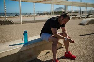 uitgeput atletisch Mens controle zijn slim pols horloge, resting na lichaamsgewicht opleiding in buitenshuis stedelijk sport- grond foto