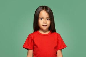 weinig meisje in rood t-shirt is glimlachen groen achtergrond foto