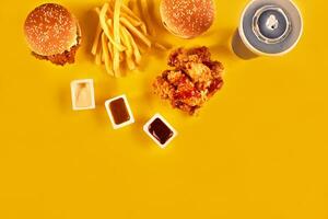 snel voedsel schotel top visie. Frans Patat, Hamburger, mayonaise en ketchup sauzen Aan geel achtergrond. foto
