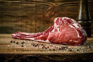 droog oud rauw tomahawk rundvlees steak met ingrediënten voor grillen foto