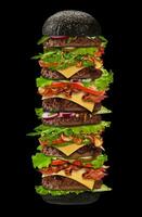 reusachtig smakelijk zwart hamburger Aan zwart achtergrond. ham, rundvlees kotelet, kaas, groenten en groenen. Koken en snel voedsel. dichtbij omhoog, kopiëren ruimte foto