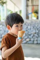 weinig Aziatisch jongen aan het eten heerlijk wit chocola ijs room foto