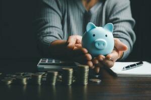 bedrijf vrouw hand- Holding varkentje bank Aan hout tafel achtergrond, besparing geld rijkdom en financieel concept, financiën, investering, financieel planning.financieel planning storting voor pensioen. foto