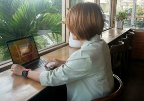 freelance zakenvrouw vervelend pak en zittend Bij de cafe werken Aan laptop gebruik makend van software internet en controle e-mail, ontwikkelen nieuw project concepten foto