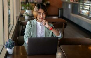 freelance zakenvrouw vervelend pak en zittend Bij de cafe werken Aan laptop gebruik makend van software internet en controle e-mail, ontwikkelen nieuw project concept foto