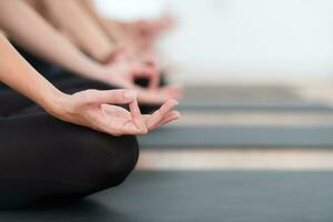 midden sectie van vrouw mediteren in lotus houding Aan oefening mat Bij huis, yoga oefening concept foto