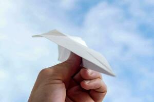 een persoon Holding een papier vliegtuig in de lucht foto