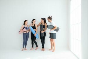 een groep van vrouw en mannetje atleten stond en babbelde in der minne in de studio voordat begin met de yoga klas. foto