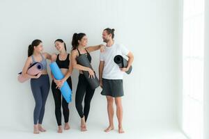 een groep van vrouw en mannetje atleten stond en babbelde in der minne in de studio voordat begin met de yoga klas. foto