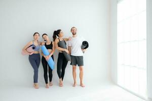 een groep van vrouw en mannetje atleten stond en babbelde in der minne in de studio voordat begin met de yoga klas. foto