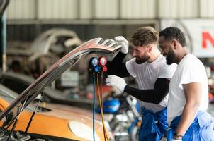 auto monteur werken in een auto reparatie winkel, inspecteren de operatie van de auto's lucht conditioner en koelmiddel. foto