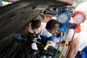 auto monteur werken in een auto reparatie winkel, inspecteren de operatie van de auto's lucht conditioner en koelmiddel. foto