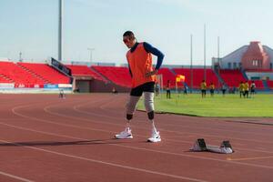 gehandicapt atletisch Mens uitrekken en opwarming omhoog voordat rennen Aan stadion bijhouden foto