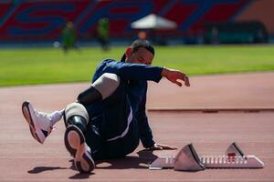 gehandicapt atletisch Mens uitrekken en opwarming omhoog voordat rennen Aan stadion bijhouden foto