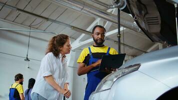 gecertificeerd ingenieur in auto onderhoud picks koppel moersleutel van werk station bank, gebruik makend van het naar vastdraaien bouten na vervangen motor. Afrikaanse Amerikaans garage arbeider vaststelling cliënt auto- foto