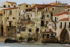 huizen langs de kustlijn en kathedraal in achtergrond, cefalu, Sicilië foto