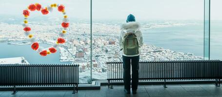 vrouw toerist bezoekende in hakodate, reiziger in trui bezienswaardigheden bekijken visie van hakodate berg met sneeuw in winter. mijlpaal en populair voor attracties in hokkaido, japan.reizen en vakantie concept foto